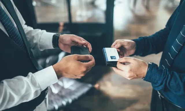 दुईजना व्यवसायीले नाम कार्ड आदानप्रदान गर्दै।
